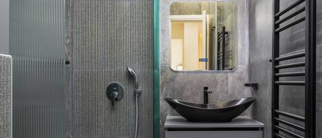 Une salle de bain moderne dotée d’une douche à parois de verre, d’un lavabo sur colonne et d’un miroir encastré.