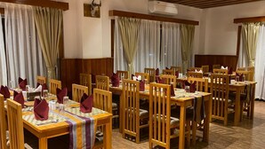 A dining area with wooden tables and chairs, arranged in rows. - Hotel Classic Wood (Punakha)