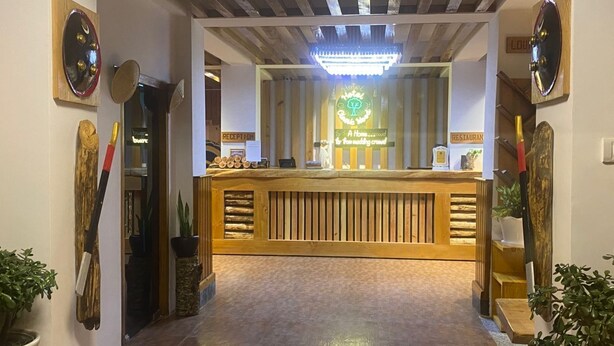 A reception area with a wooden reception desk, a reception sign, and a sign indicating a restaurant. - Hotel Classic Wood (Punakha)