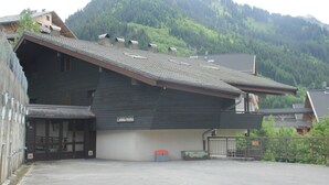 Ein Gebäude mit einem schrägen Dach, einer Schilder mit der Aufschrift „L'ANNEMARIE“ und einem eingezäunten Parkplatz.