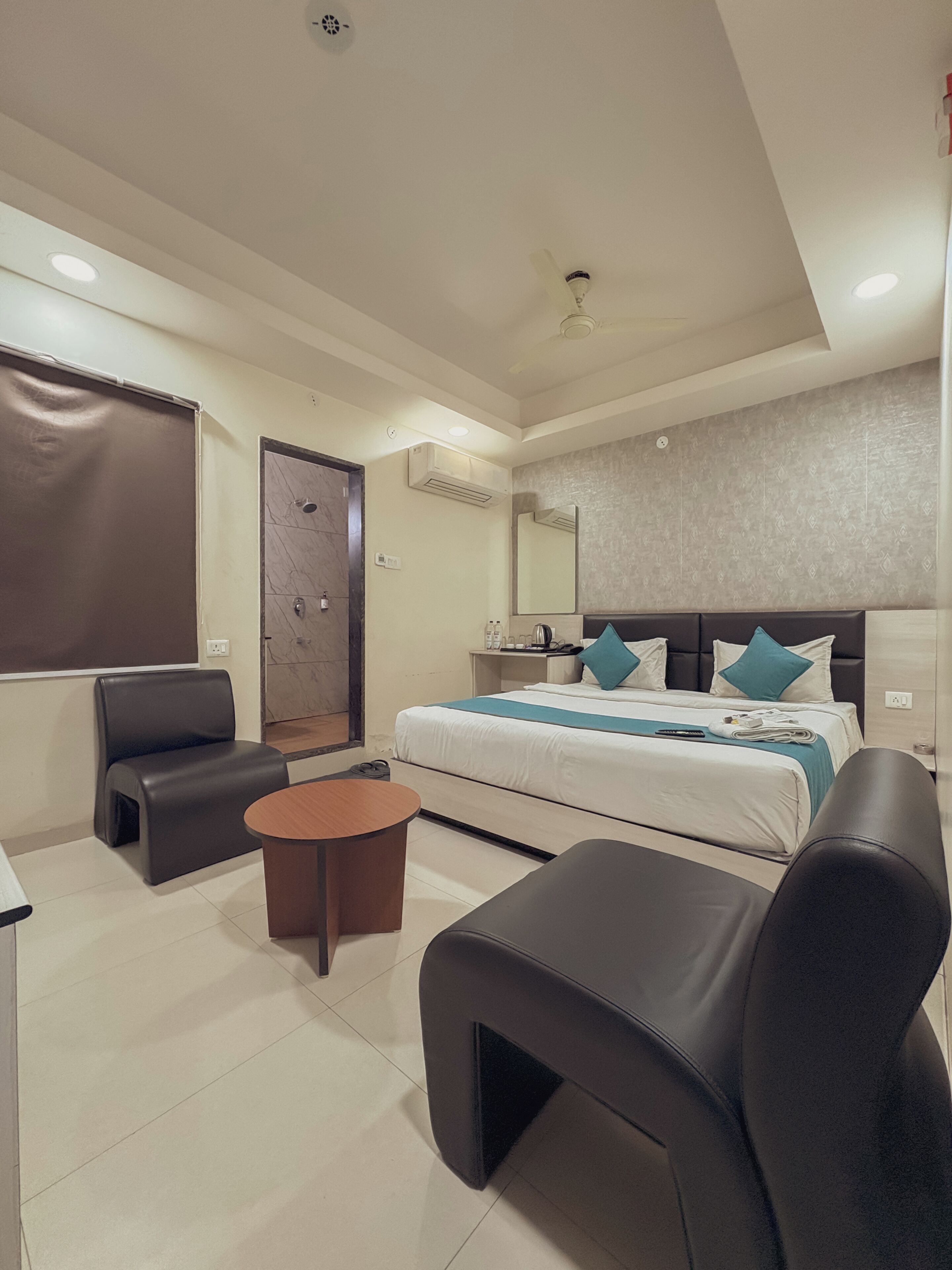 A modern hotel room with a bed, a desk, a chair, and a small table.