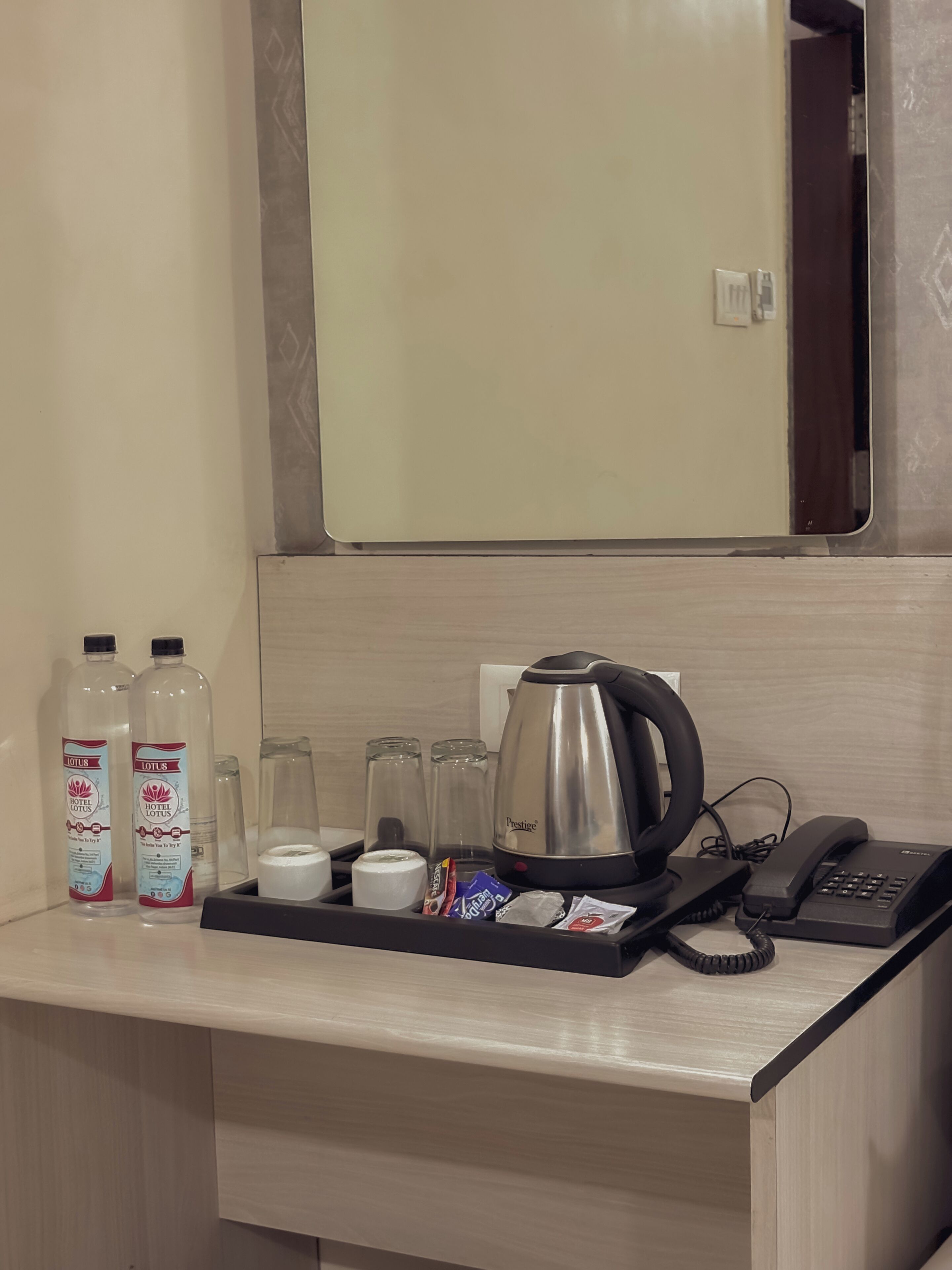 A hotel room's minibar with toiletries, a coffee maker, and a phone.