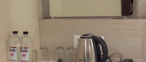 A hotel room's minibar with toiletries, a coffee maker, and a phone.