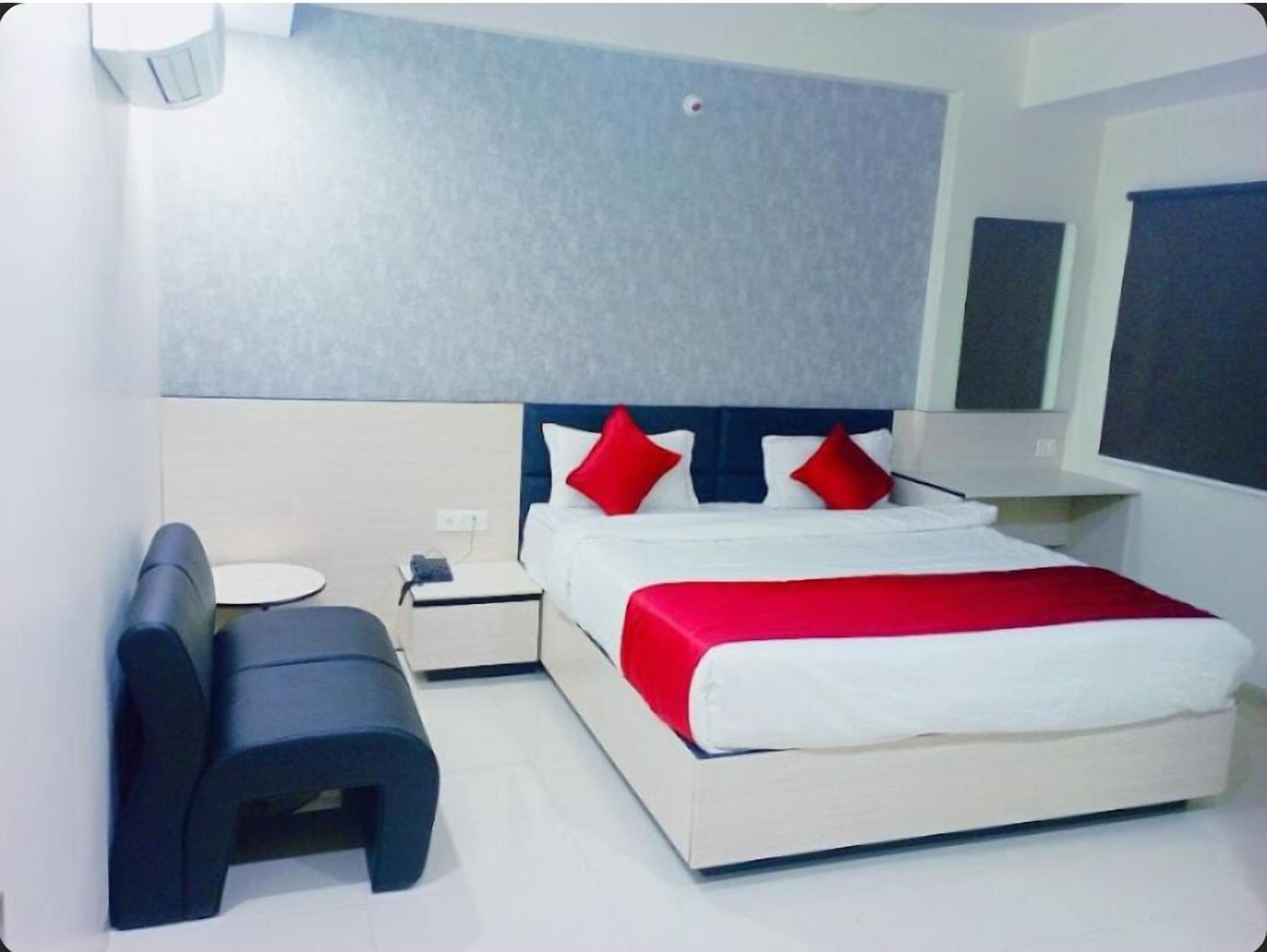 Una habitación de hotel moderna con una cama grande, una mesita de noche, un escritorio y un banco.