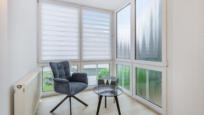 Et moderne værelse med et stort vindue, en stol og et lille bord med to glas.
