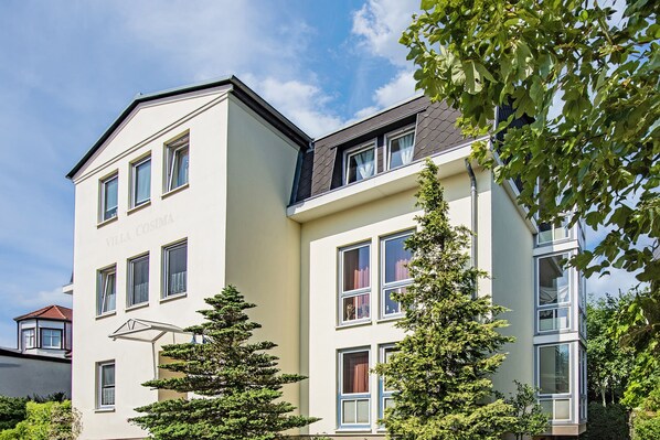 A multi-story building with a flat roof, large windows, and a sign reading "Villa Cosima."