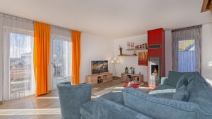 A modern living room with a large sofa, a TV, and a fireplace.