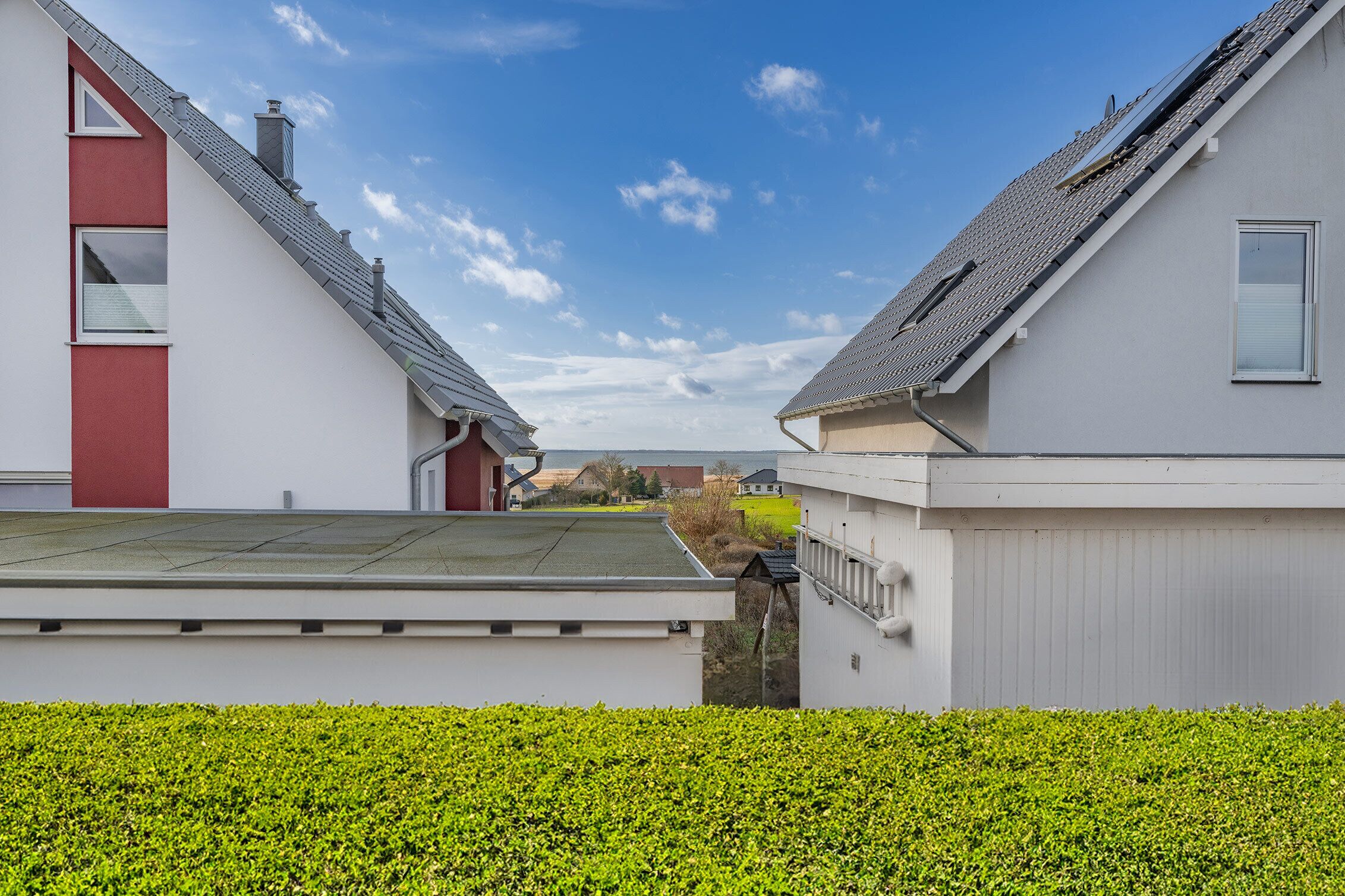 A residential area with modern houses, a clear sky, and well-maintained greenery.