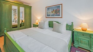 Une chambre à coucher avec un grand lit, des tables de chevet vertes et une lampe fixée au mur.
