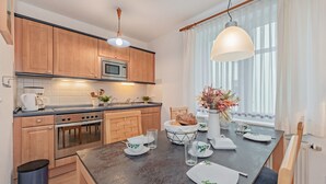 Une cuisine moderne avec des meubles en bois, un four à micro-ondes encastré et un coin repas avec une table mise pour deux personnes.