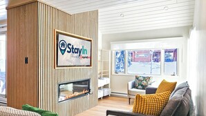 Een moderne woonkamer met een open haard, een StayIn bord en uitzicht op het buiten.