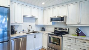 Een moderne keuken met roestvrijstalen apparatuur, witte kasten en een houten vloer.