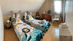 A bedroom with two beds, a dresser, a chair, a table, and a basket. - For rent: 2 bedrooms (1 with double bed, convertible into 2 twin beds). (Vienne-en-Val)