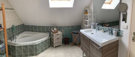 A modern bathroom with a freestanding bathtub, a vanity with a mirror, and a small stool.
