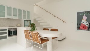 Une cuisine moderne dotée d’un îlot central, de meubles blancs et d’un escalier menant à un étage supérieur.