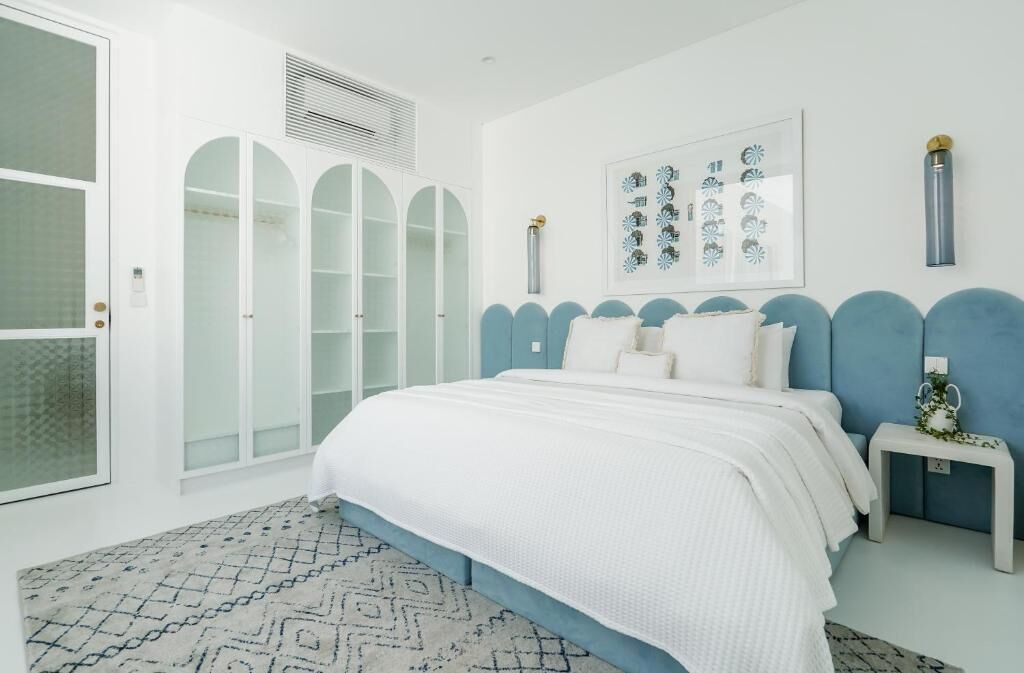A bedroom with a large bed, a wardrobe, and a framed artwork on the wall.
