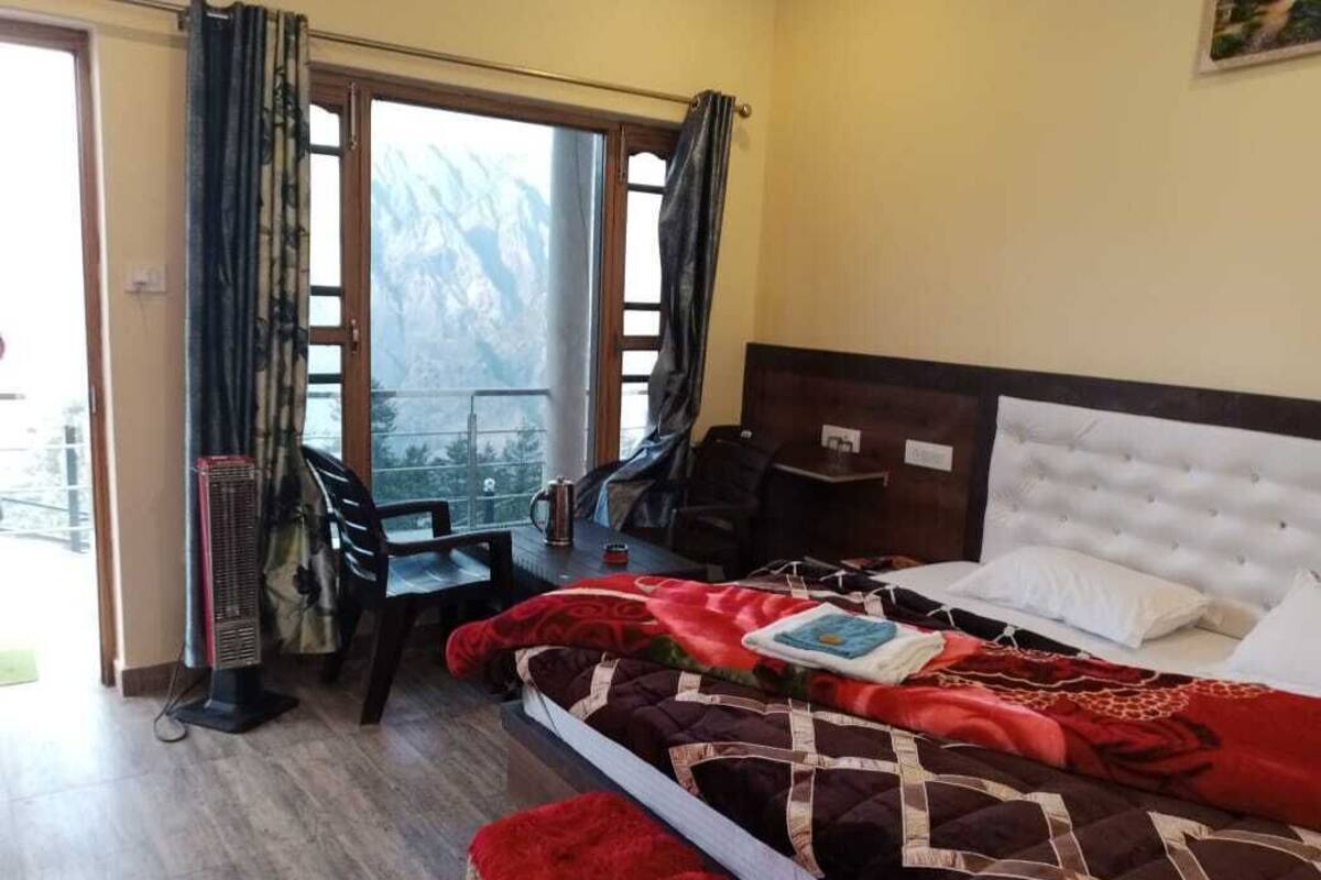 Habitación de hotel con cama, una mesa y una silla cerca de una ventana con vistas.