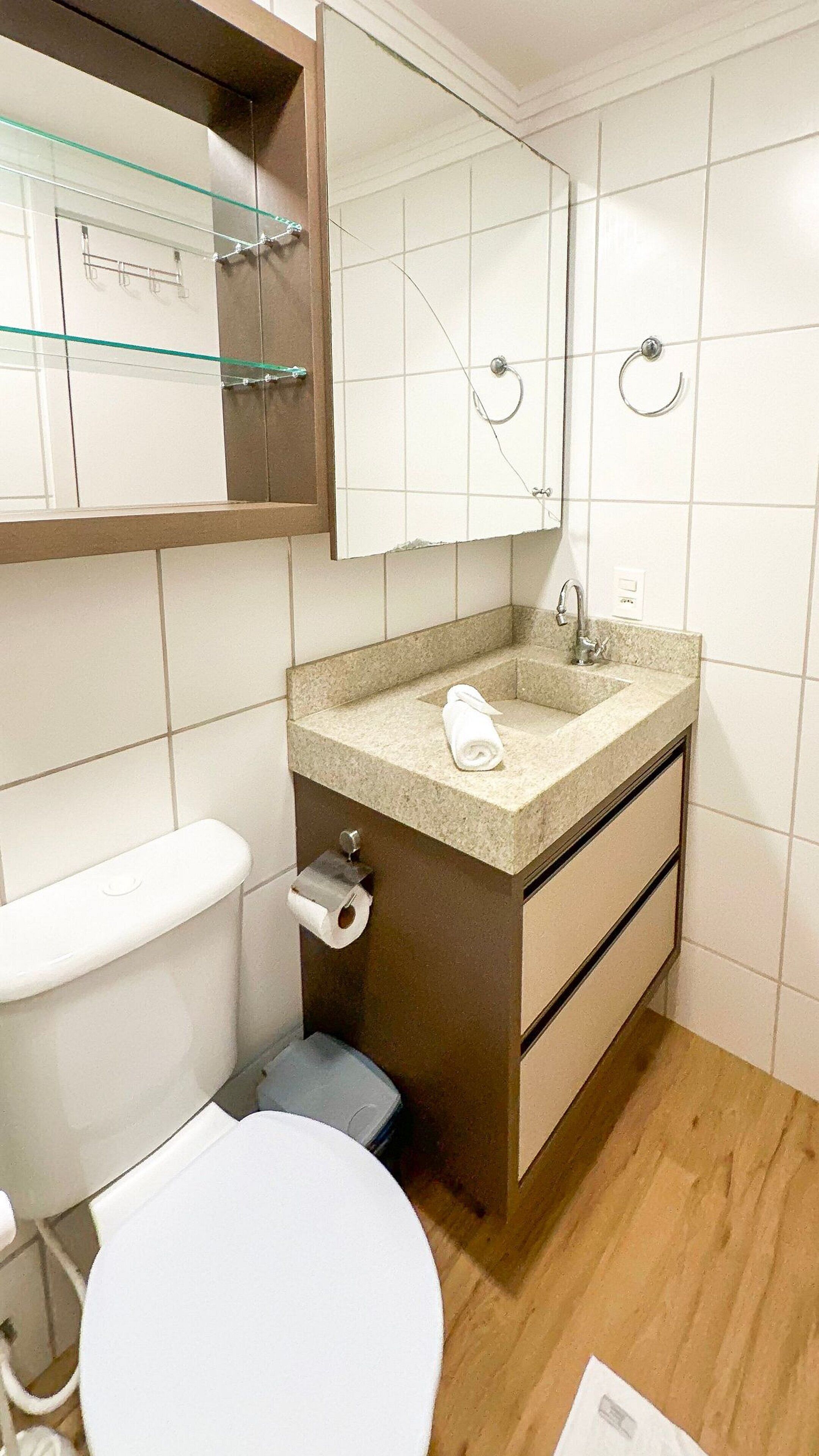 Een badkamer met toilet, wastafel en spiegel.