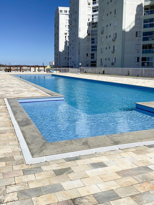 Una piscina rectangular con borde de azulejos, rodeada por una terraza de piedra.