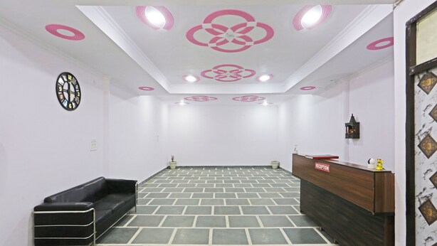 A reception area with a reception desk, a black sofa, a clock, and patterned floor tiles. - Twamev Residency  (New Delhi)