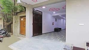 A building entrance with a wooden door, a tiled floor, and a staircase leading inside. - Twamev Residency  (New Delhi)