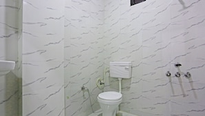 A bathroom with a toilet, a sink, and a shower. - Twamev Residency  (New Delhi)