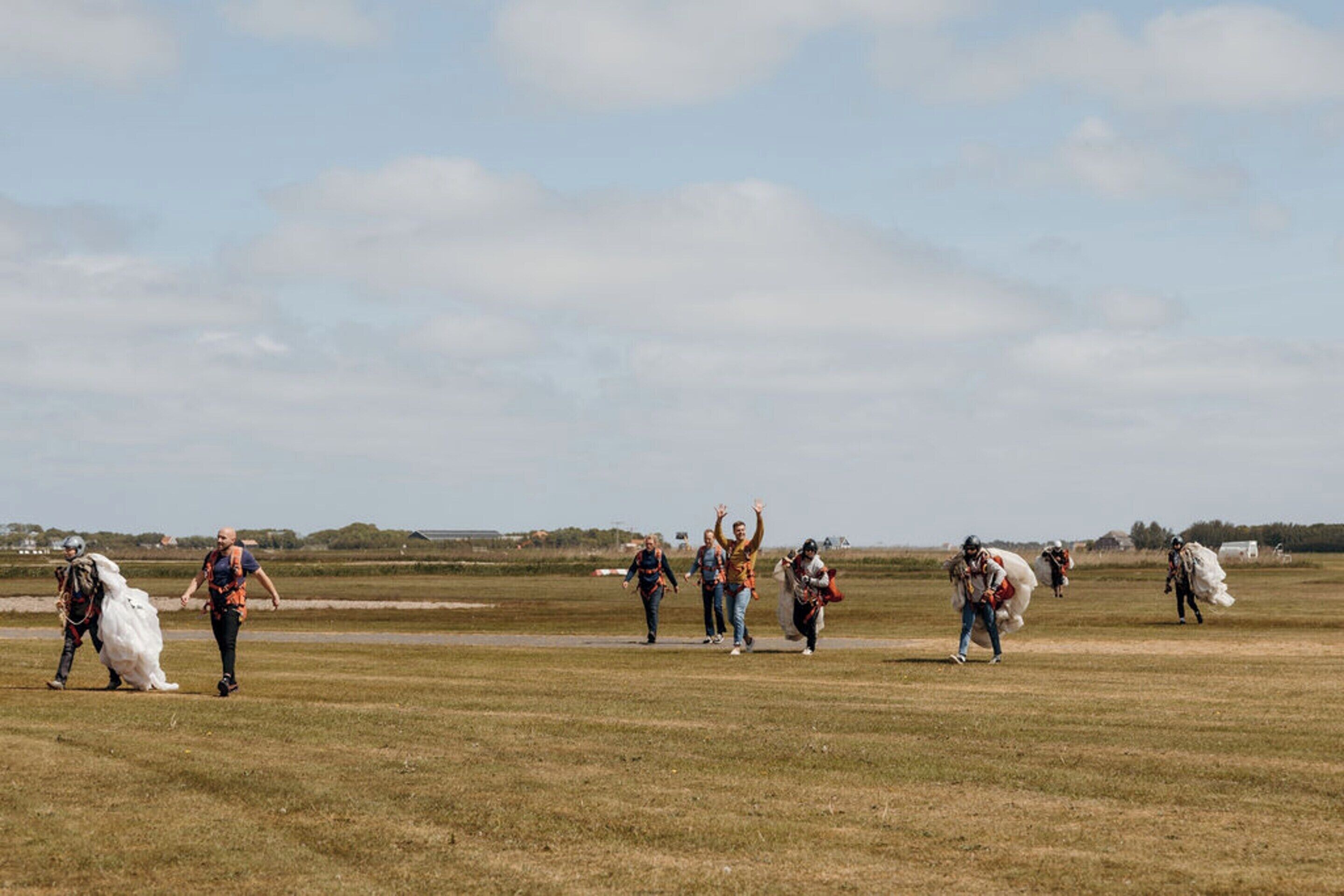 A group of people in a grassy field, some carrying large white objects.