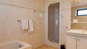 Een badkamer met een badkuip, douchecabine, wastafel en spiegel.