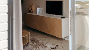 A modern living room with a TV on a wooden cabinet, a small table, and a rug.