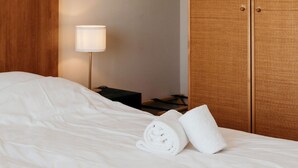 A hotel room with a neatly made bed, a lamp, and a wardrobe.