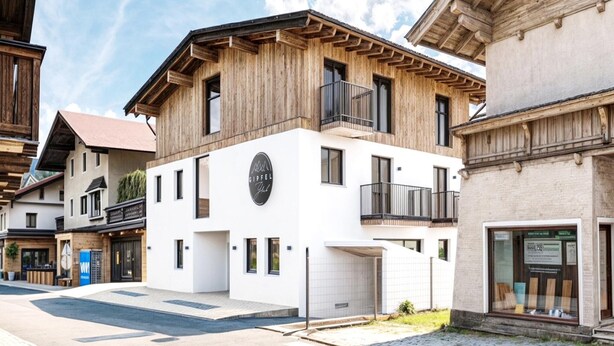 Un bâtiment moderne avec une façade blanche, des balcons en bois et un logo bien visible.