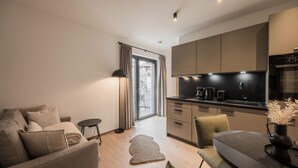 Un appartement moderne comprenant un espace de vie, une kitchenette et une porte-fenêtre coulissante donnant sur une terrasse extérieure.