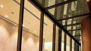 A modern interior with glass walls, a marble floor, and a large cylindrical column. - The Galleria Residence by Hava  (Ho Chi Minh City)