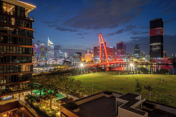 Un paisaje urbano con un puente rojo llamativo, edificios modernos y un río.