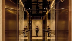An elevator with a marble floor and glass walls, leading to a mirrored interior. - The Galleria Residence by Hava  (Ho Chi Minh City)
