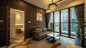 A modern living room with a sofa, coffee table, and large windows offering a city view. - The Galleria Residence by Hava  (Ho Chi Minh City)