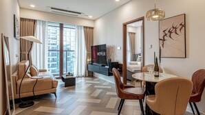 A modern living room with a sofa, TV, dining table, and chairs. - The Galleria Residence by Hava  (Ho Chi Minh City)