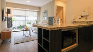 Una cocina moderna con encimera de granito, microondas integrado y armario de madera oscura.