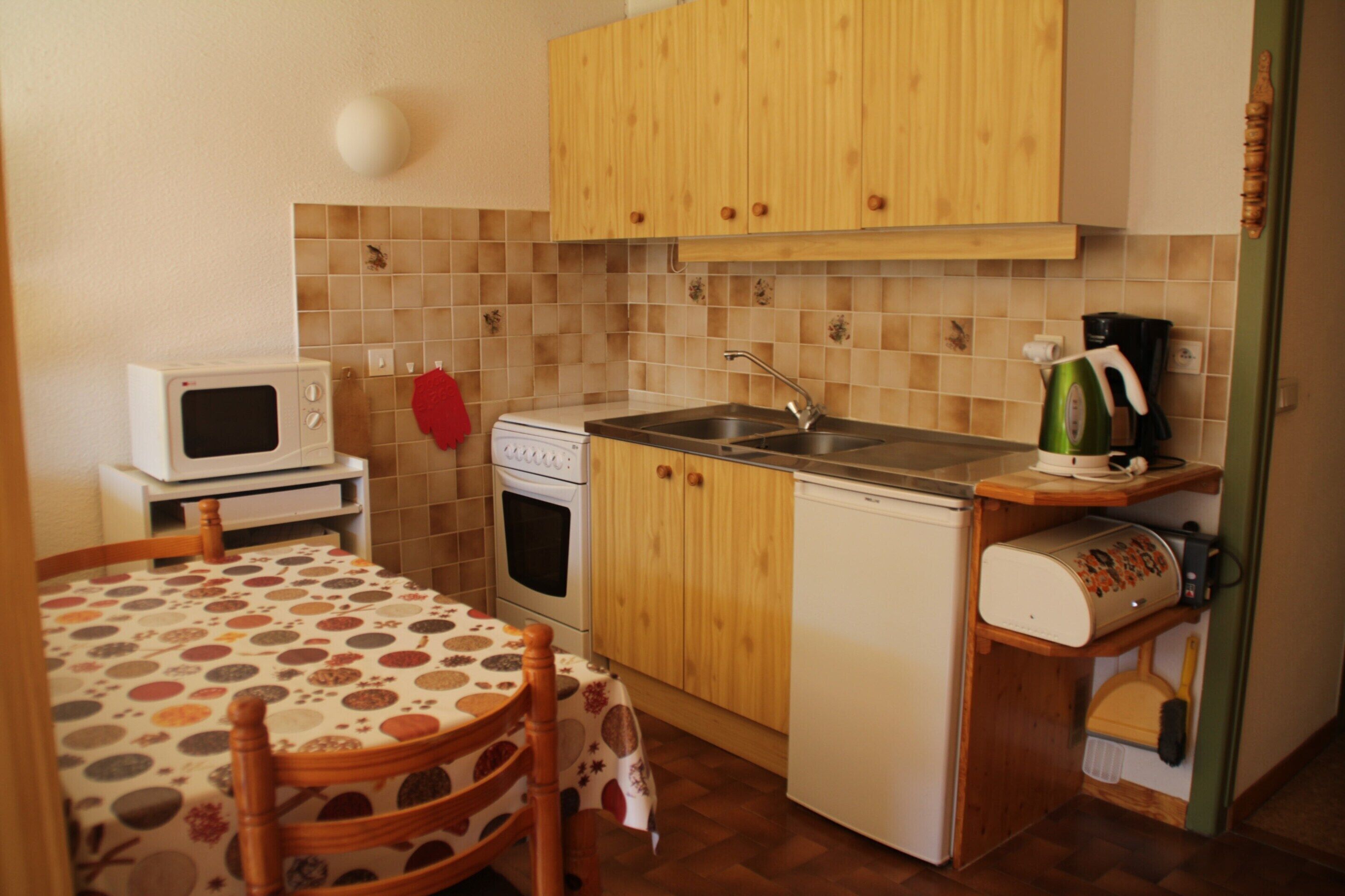 Una cucina compatta con mobili in legno, un forno a microonde, un piano cottura e un lavello.