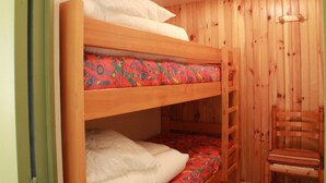 Ein Etagenbett mit farbigem Topper und weißer Bettwäsche.