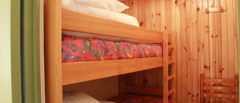 Un lit superposé avec un matelas coloré et du linge de lit blanc.