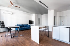 A modern living space with a kitchen area, a dining table, a blue sofa, and a ceiling fan. - Boulevard 114 (Tashkent)