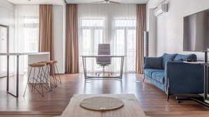 Een moderne woonkamer met een bank, een eettafel met krukken en een plafondventilator.