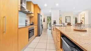 Een moderne keuken met houten kastjes, roestvrijstalen apparatuur en een granieten aanrecht.