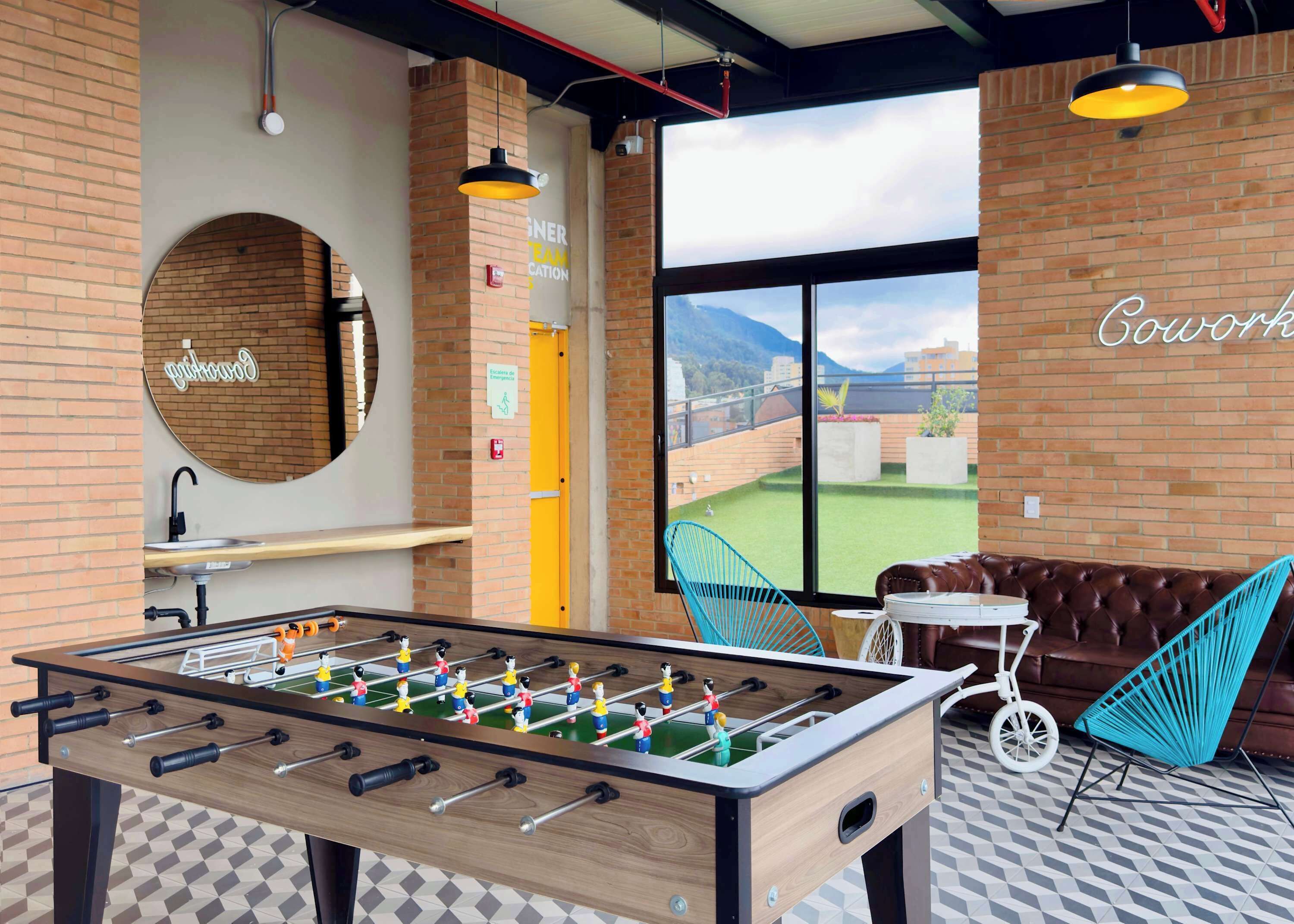 Een moderne binnenruimte met een tafelvoetbaltafel, een bar en een zithoek met uitzicht op het buitengebied.