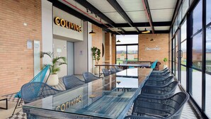 A modern coworking space with a glass table, blue chairs, and a brick wall. - w* | Radiant Loft w/ balcony in Chapinero (Bogotá)