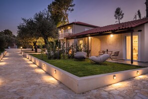 Una casa moderna con un camino de piedra que lleva a un césped cuidado y un área de estar al aire libre.