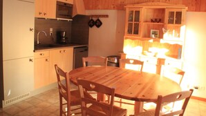 Una cucina compatta con mobili in legno, un tavolo da pranzo e sedie.