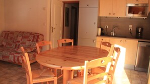 Una cucina accogliente con un tavolo e sedie in legno, un divano e un frigorifero.