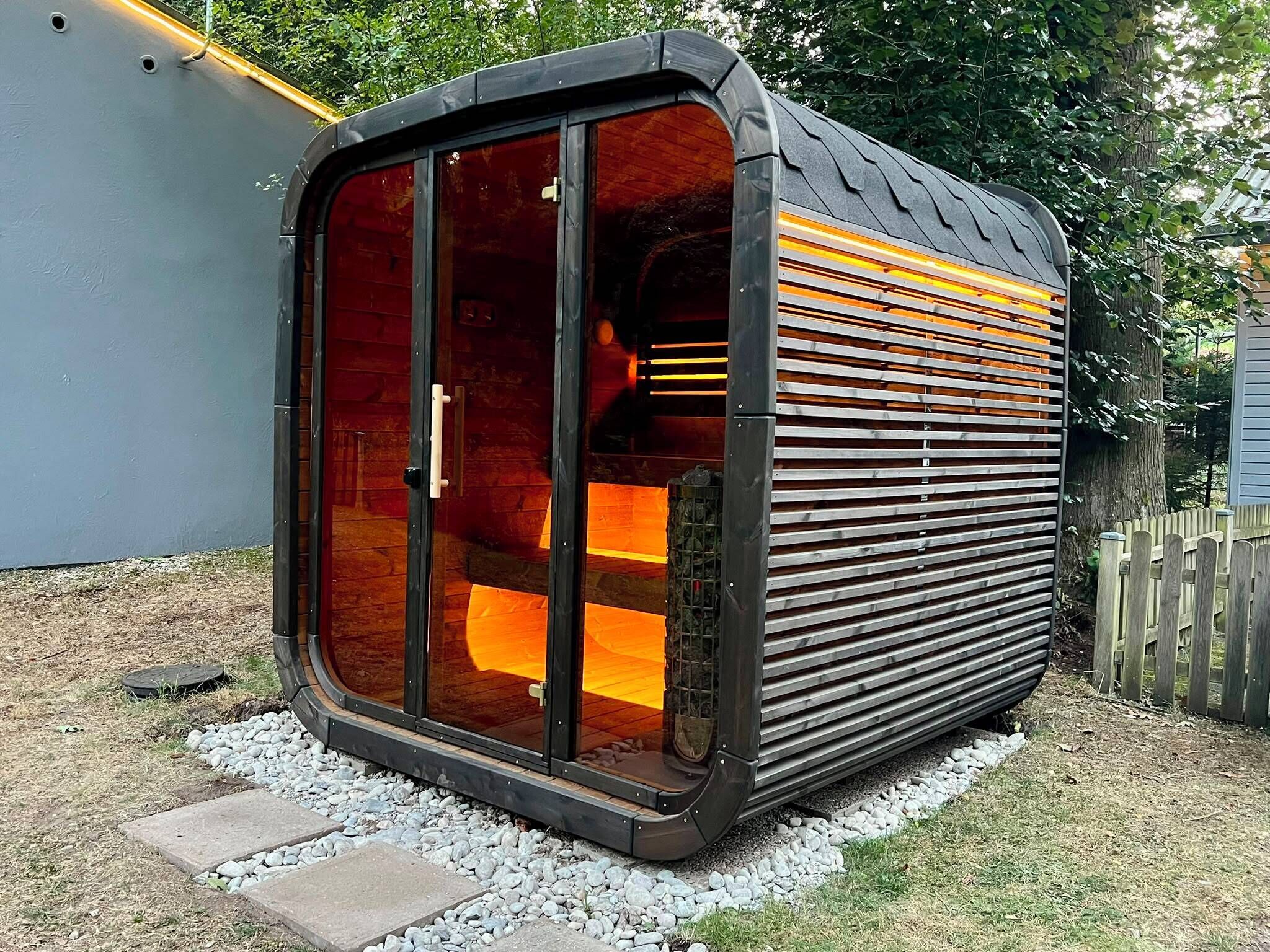 Ein kompakter, moderner Bau mit einer großen Glasdoor, einer Metallfassade und einem Holzinneren.